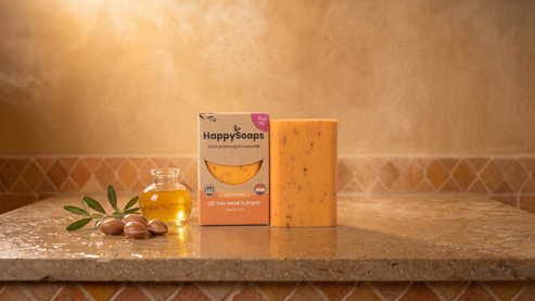 Argan Oil and Rosemary Body Wash Bar on warm marble with argan oil, argan nuts and an olive sprig