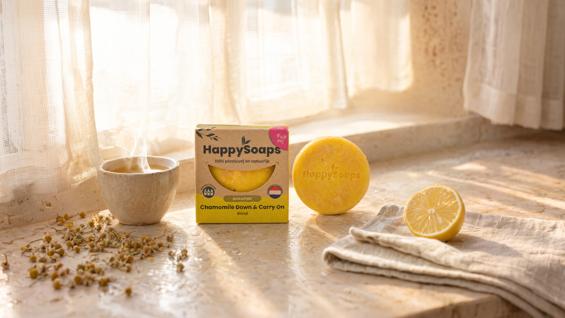 Chamomile Down & Carry On Shampoo Bar on a windowsill with chamomile tea, chamomile flowers and lemon